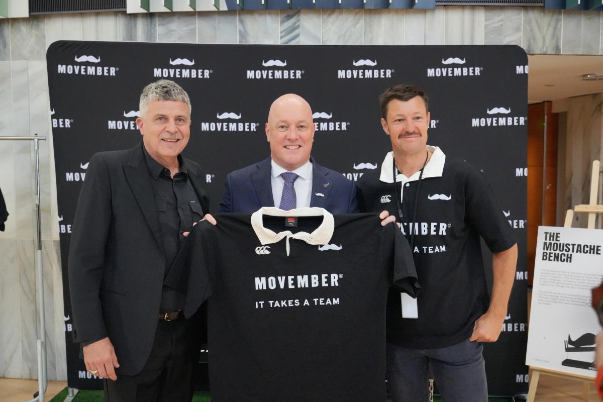 Left to right: Movember Founder Travis Garone, NZ Prime Minister Christopher Luxon & Movember NZ Country Manager, Robert Dunne pose together and smiling for the camera with Movember merch