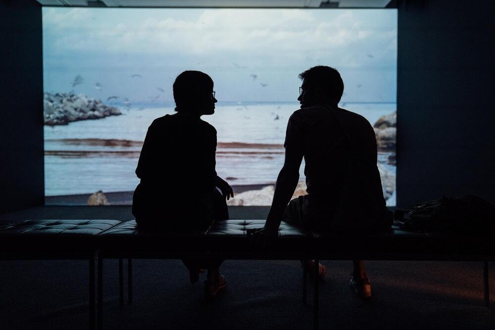 A man and a woman sitting in a dark room talking 