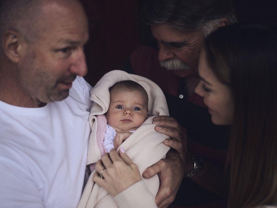 Photo of a family lovingly doting over an infant.