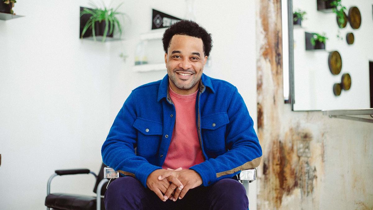 A man smiles from his chair in a barbershop