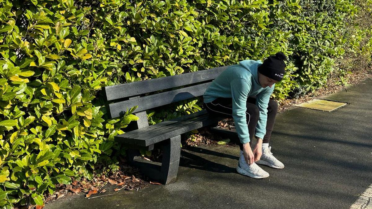 Rich on a bench tying his shoe lace, getting ready to run