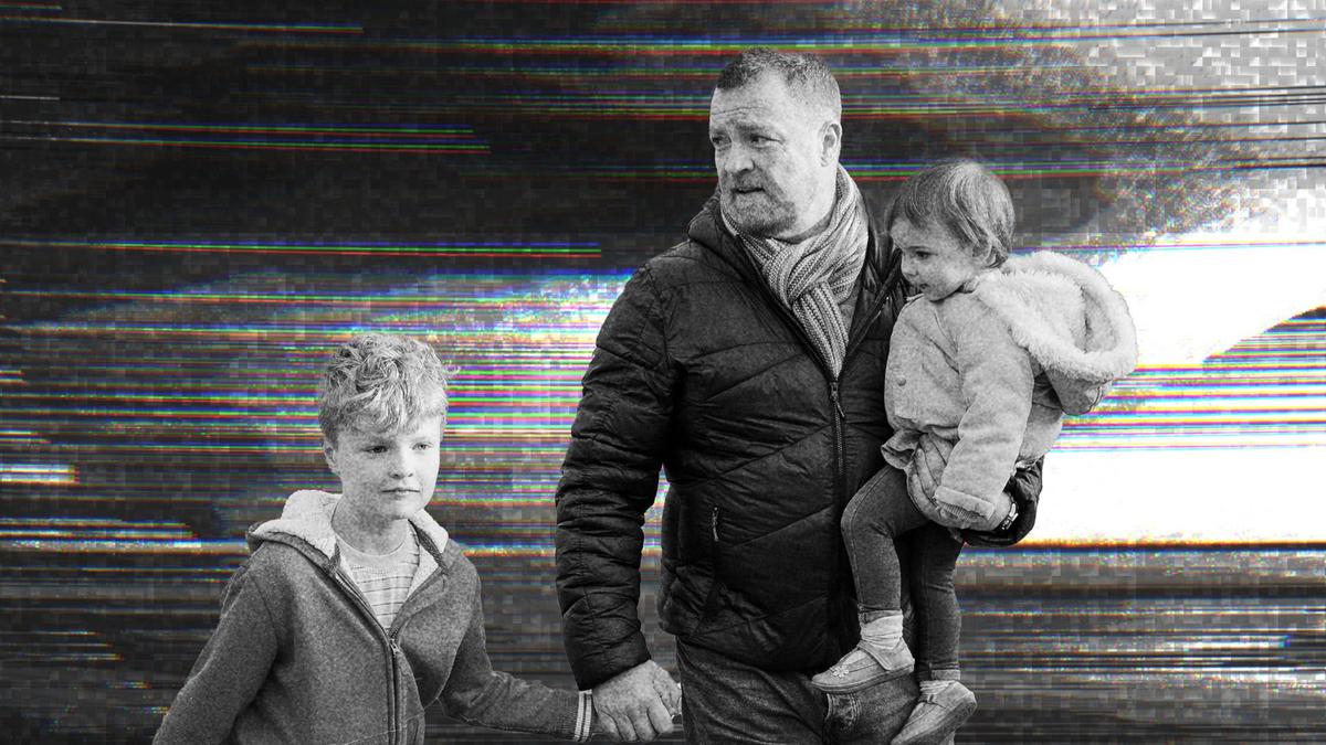 A father walking with his two children.