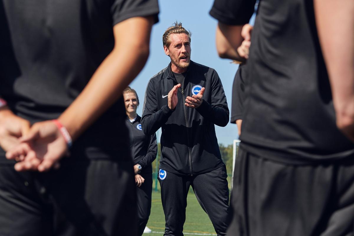 A soccer coach talking to young soccer players at practice 