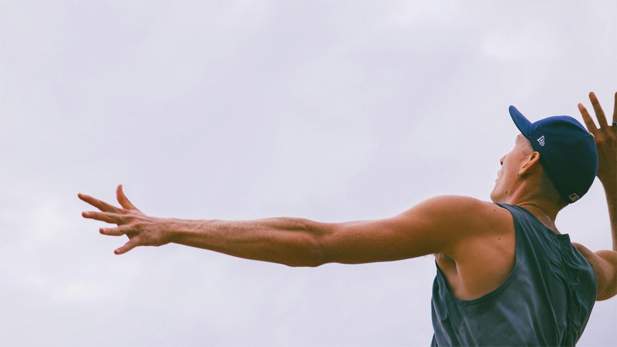 A man winds up, arm raised, ready to spike a volleyball 