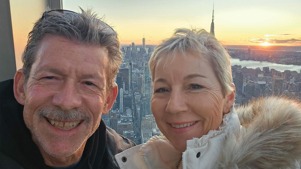 Mark and his wife in front of a city landscape