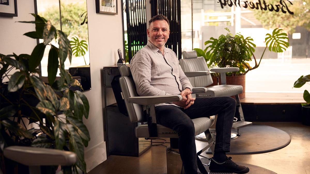 Mo Bro Ben sits in a barber chair at Brother Wolf barbershop, St. Kilda.