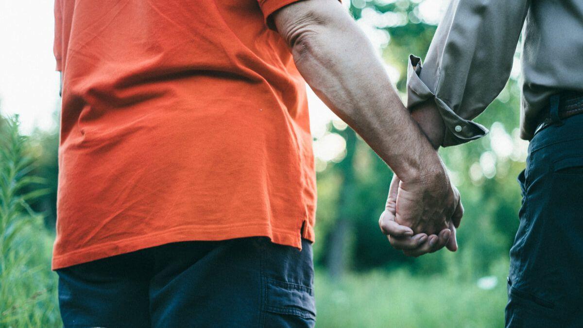 Two men walking outdoors holding hands