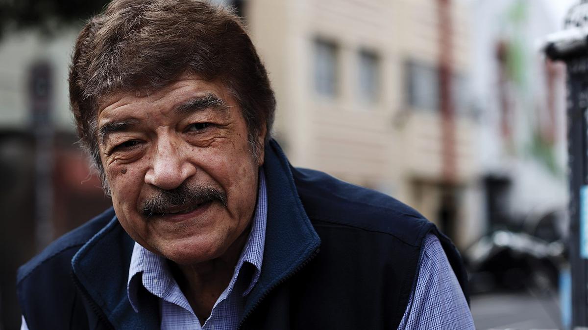 A photo of a moustachioed man smiling towards the camera.