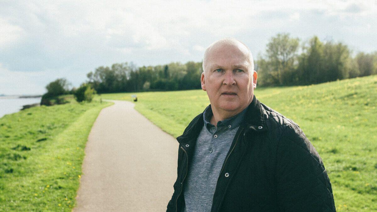 Man walking outdoors in a park next to a lake