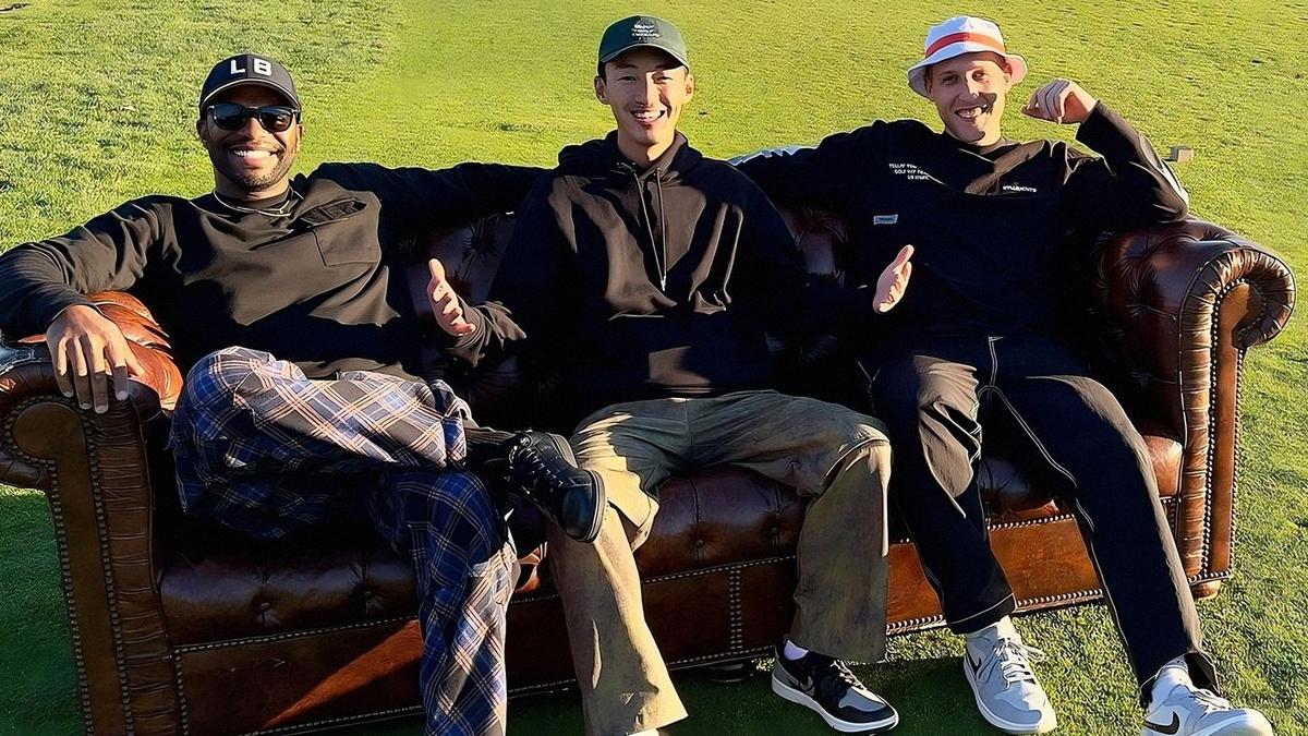 3 friends lounge on a large leather cough in the middle of a golf course surrounded by mountains