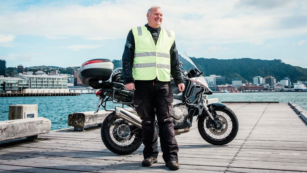 DGR ride host Richard stands on a wharf next to his motorcycle.