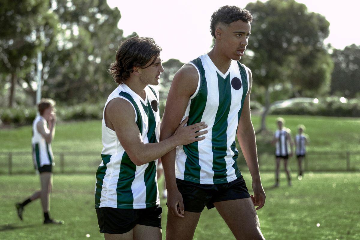 Two young male AFL footy players on the field 