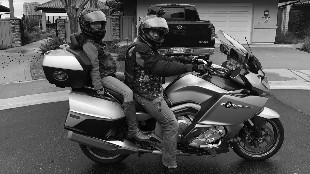 A man sits on his motorcycle with a female passenger seated behind him