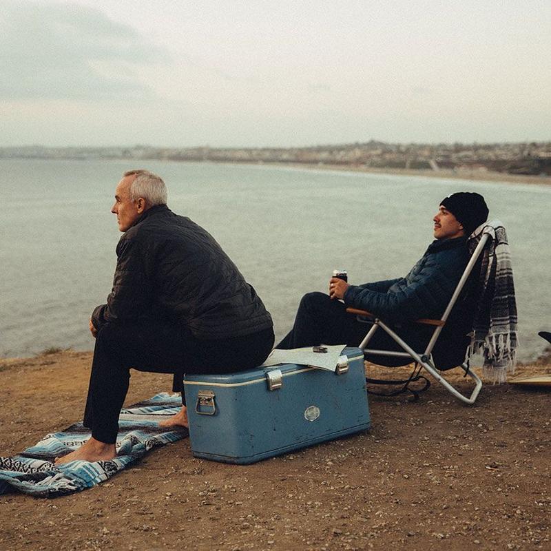 Two middle age men sitting by the water 