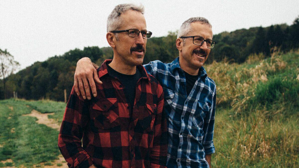 Two men walking arm over shoulders outdoors in nature