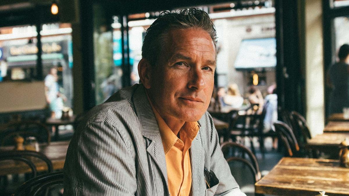 A man sitting in a cafe with a slight smile.
