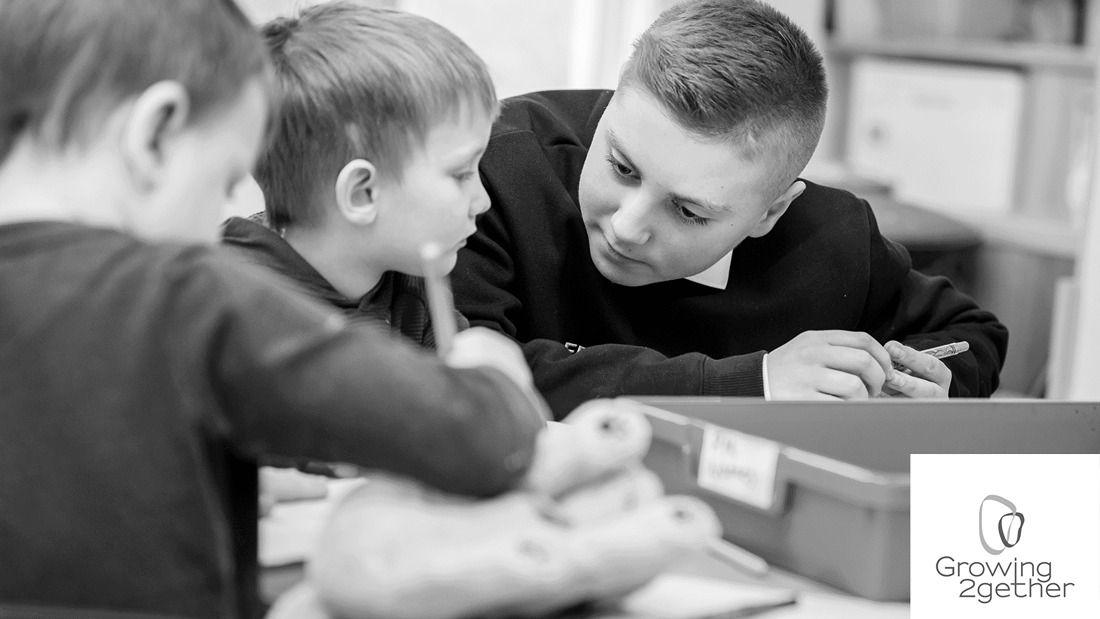 Teenage boy helping nursery boy read