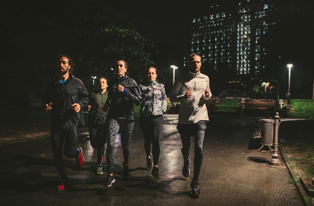 A group of people are running together through a park at night time