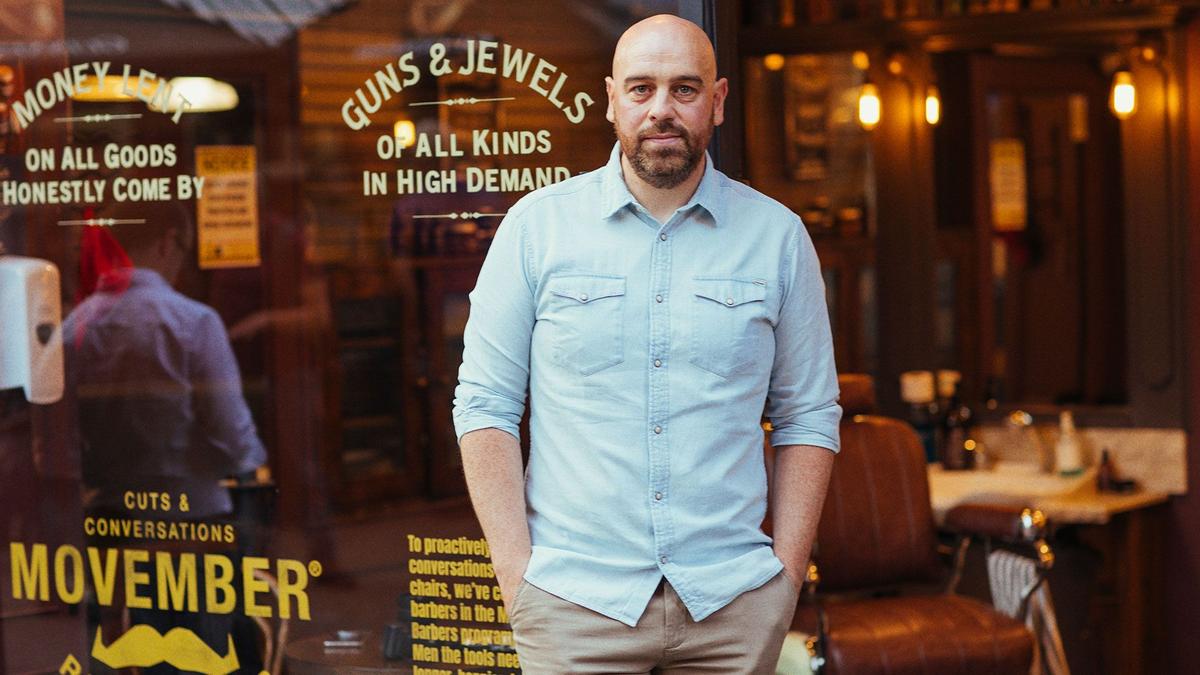 A photograph of a man outside a barber shop