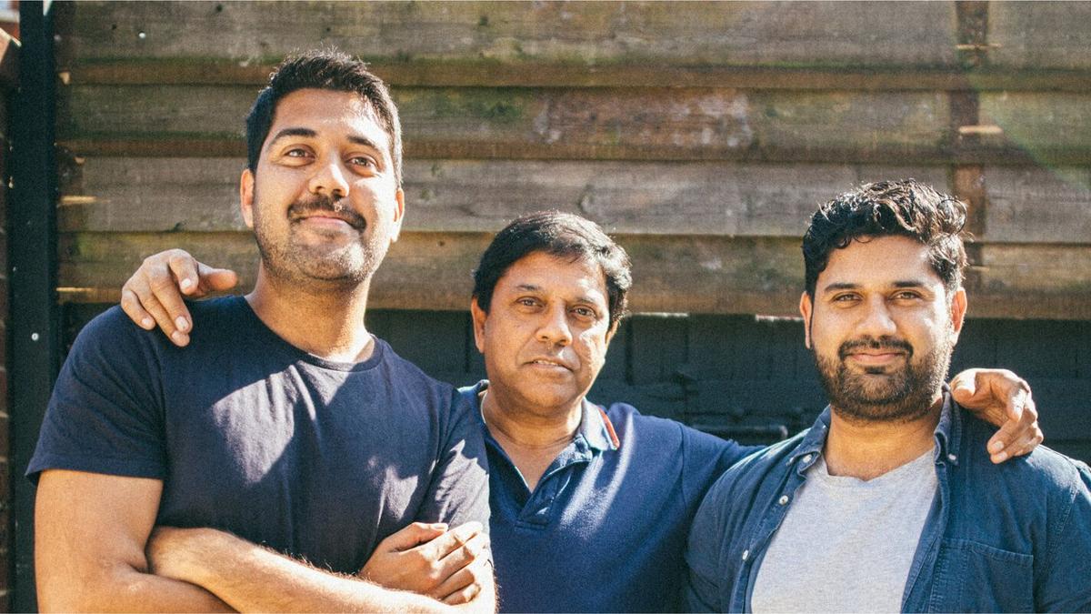 An older man standing with his arms around two younger men