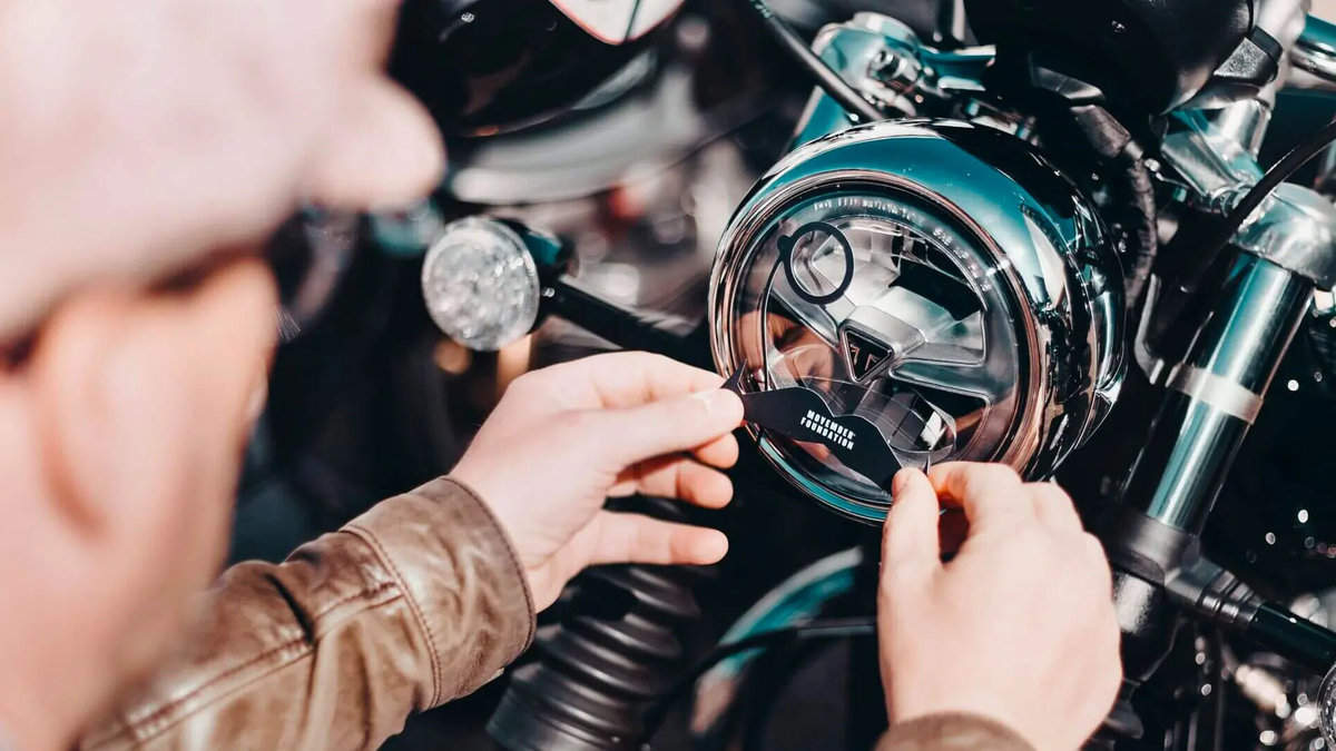 A DGR rider applies a Movember decal to his headlamp.