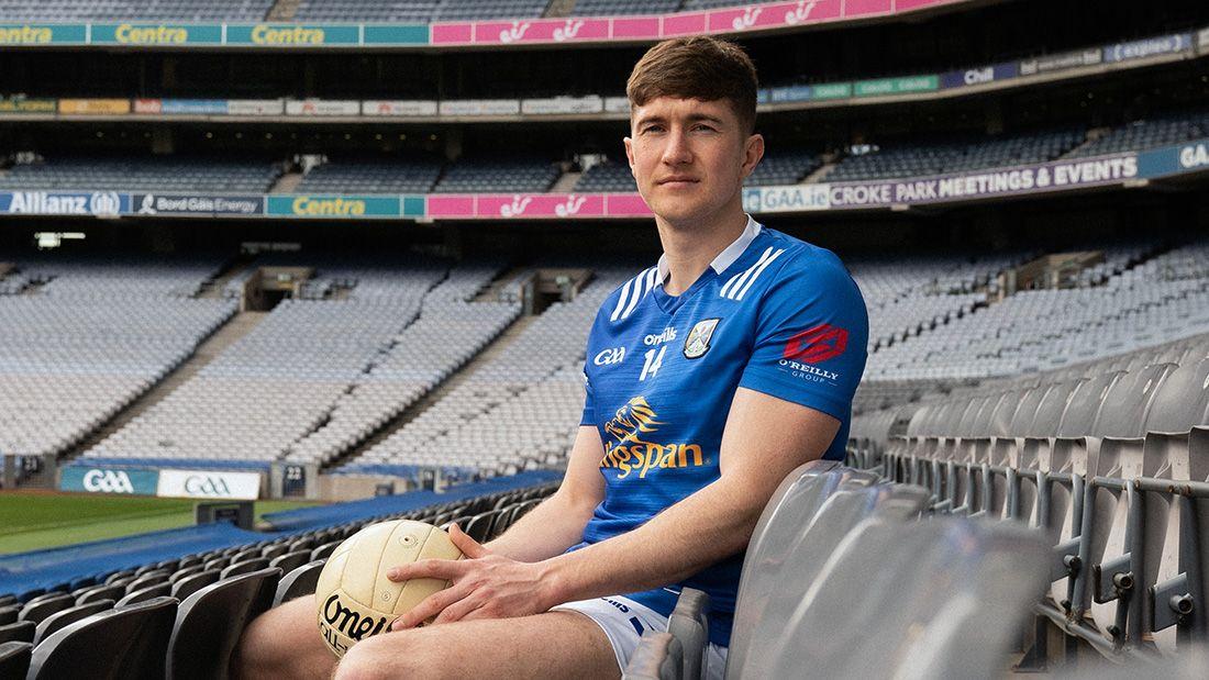 Footballer Oisín Kiernan sitting in Croke Park Stadium stalls, holding a football.