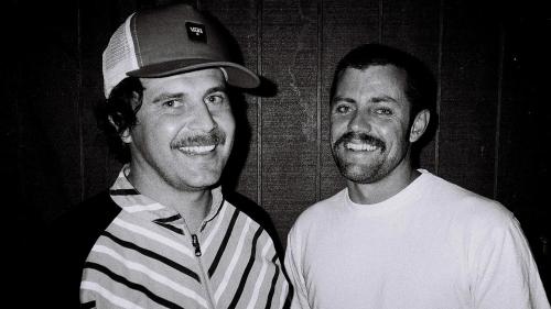 A black and white photo of two men smiling at the camera