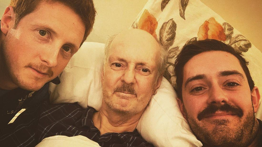 Aldwyn with his dad and brother smiling for camera showing off their moustaches