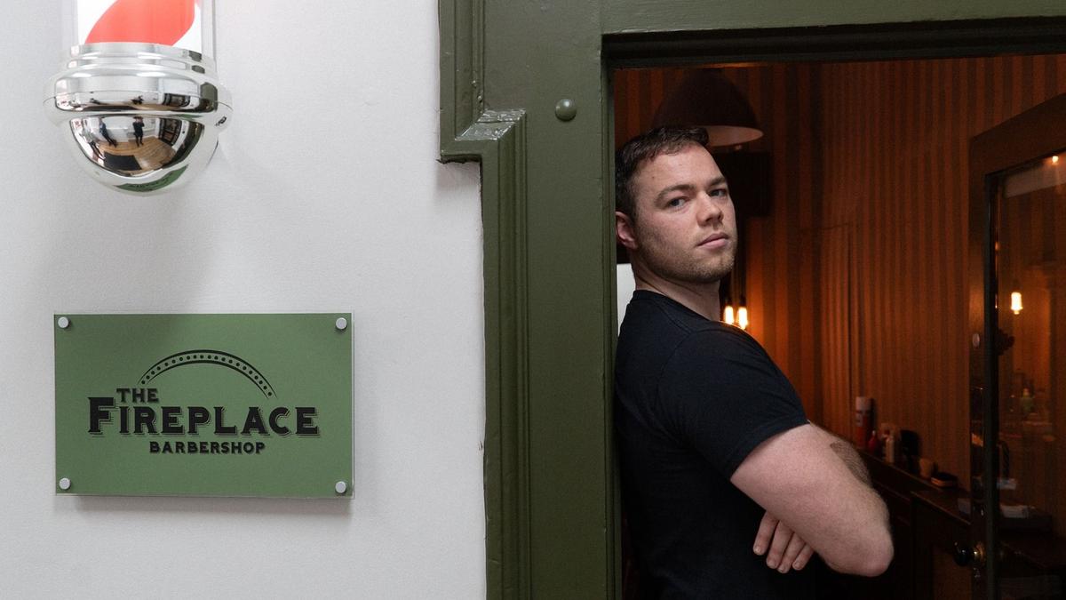 Cian leaning against the door of a barber shop