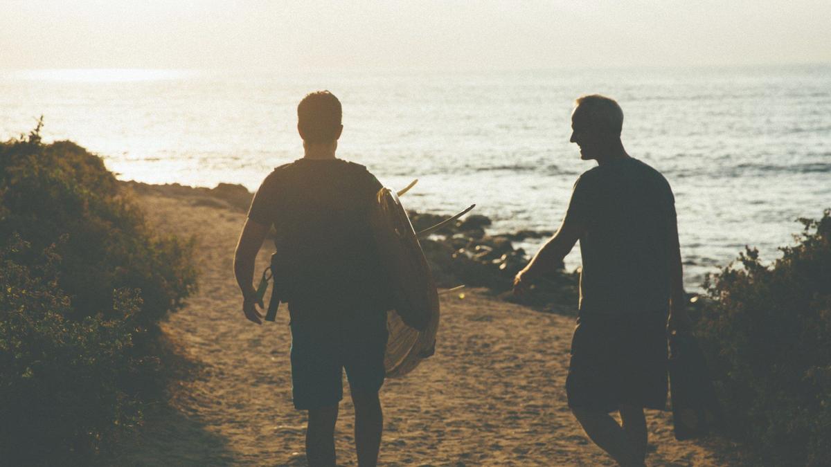 Two men carrying surf boards by the shore