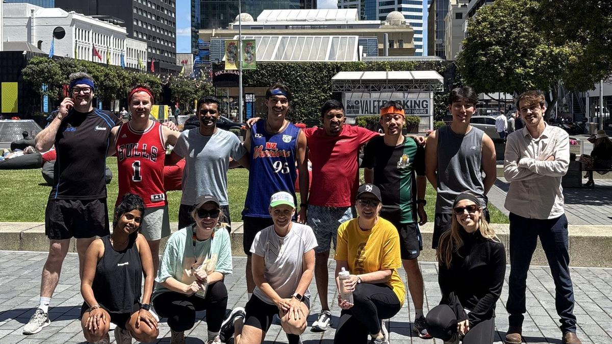 Group of people standing in street in sports gear posing for photo on sunny day