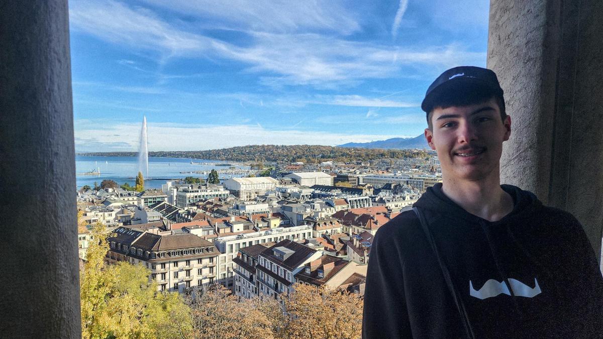 Young man at lookout with European city below with lake in background.