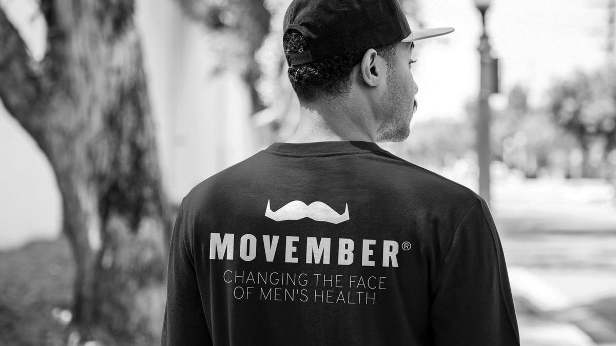 Photo of a man from behind, wearing a Movember t-shirt that reads "Movember: Changing the Face of Men's Health"