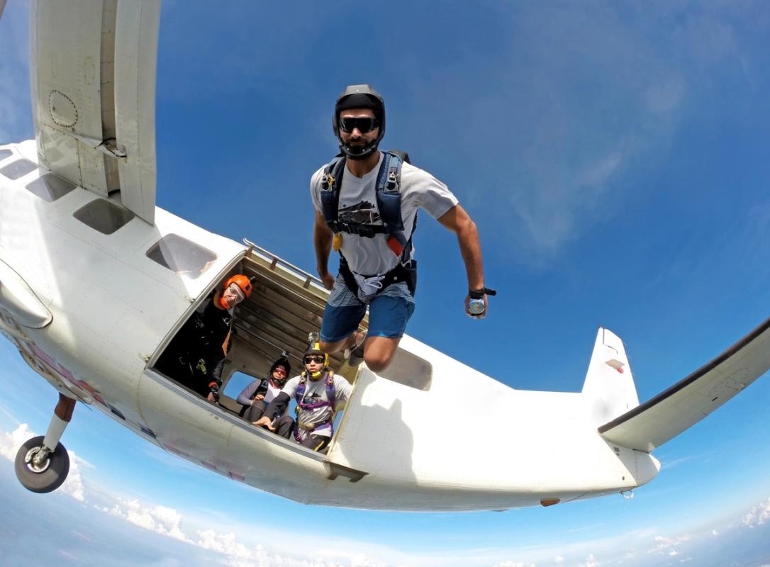 A man is jumping out of a plane wearing a skydiving gear
