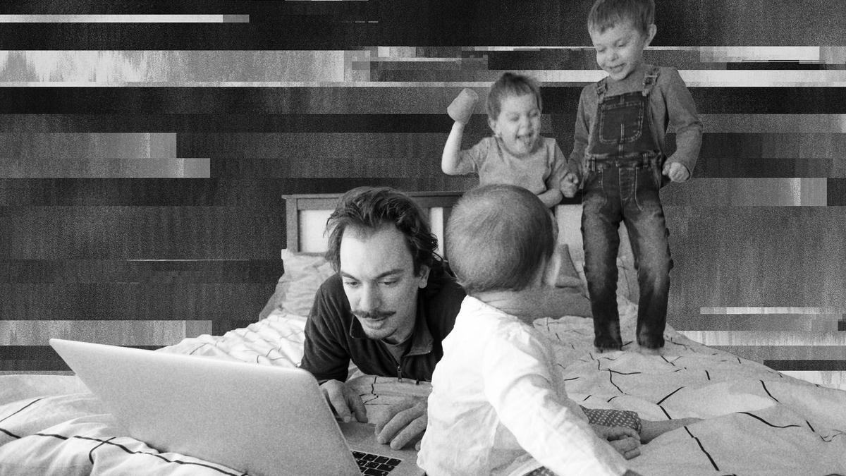 A father with his three kids jumping on the bed around him.