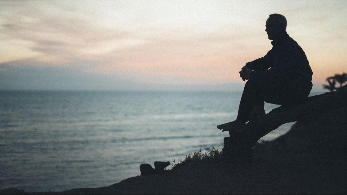Man sitting on tree log and looking out over the ocean