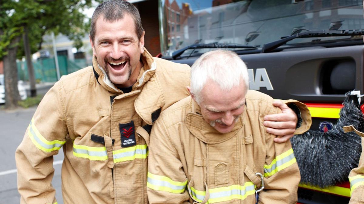 Deux pompiers se tenant par les épaules et souriant