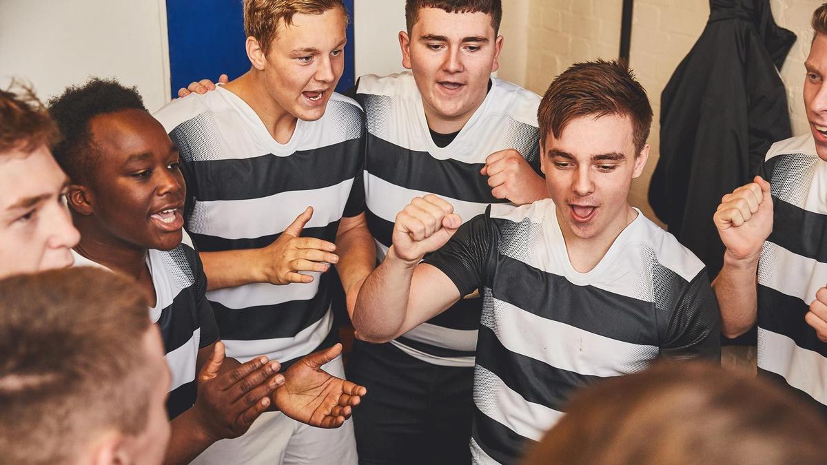 A junior rugby team in a team huddle in the changing rooms
