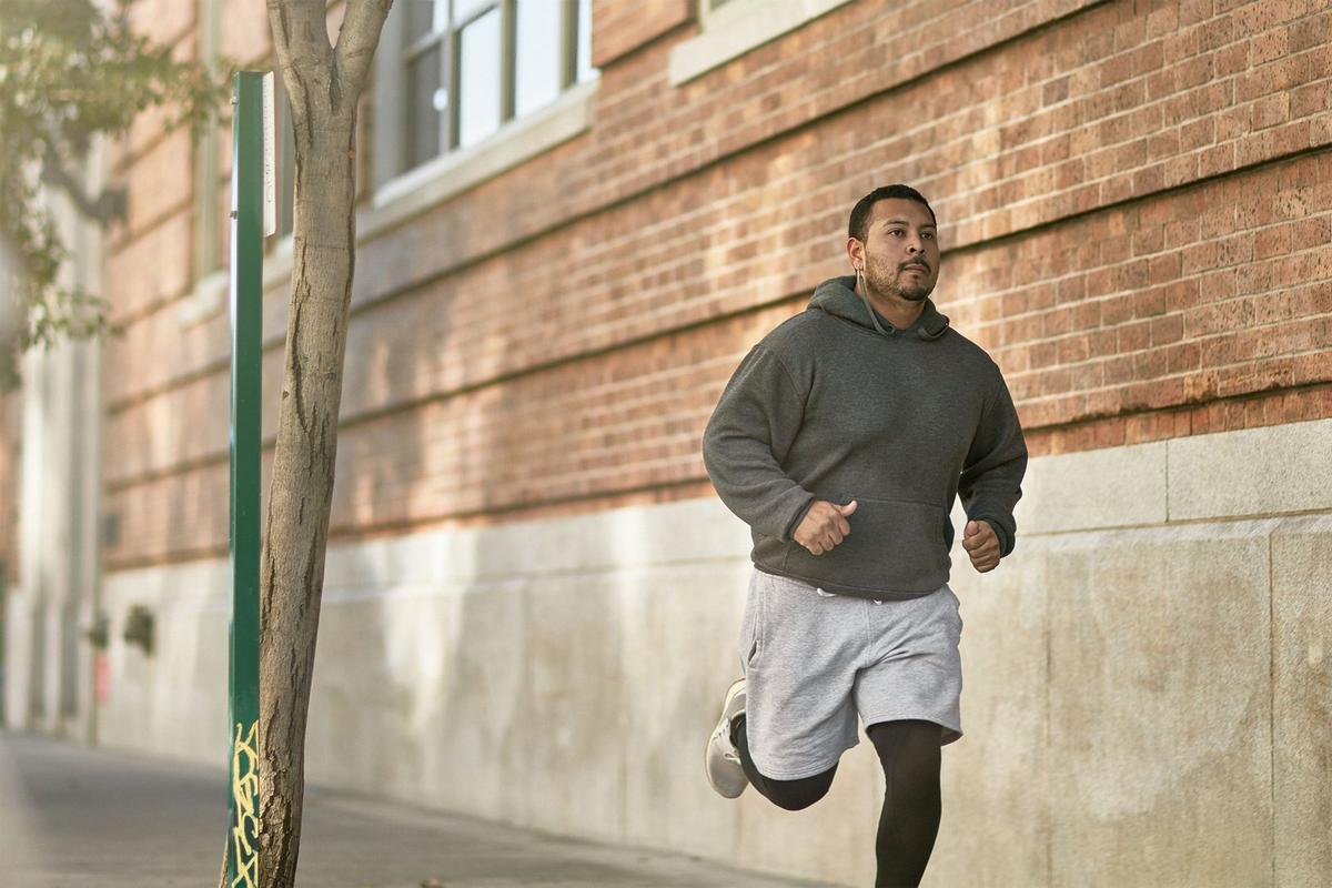A man running along an urban street past a brick building.