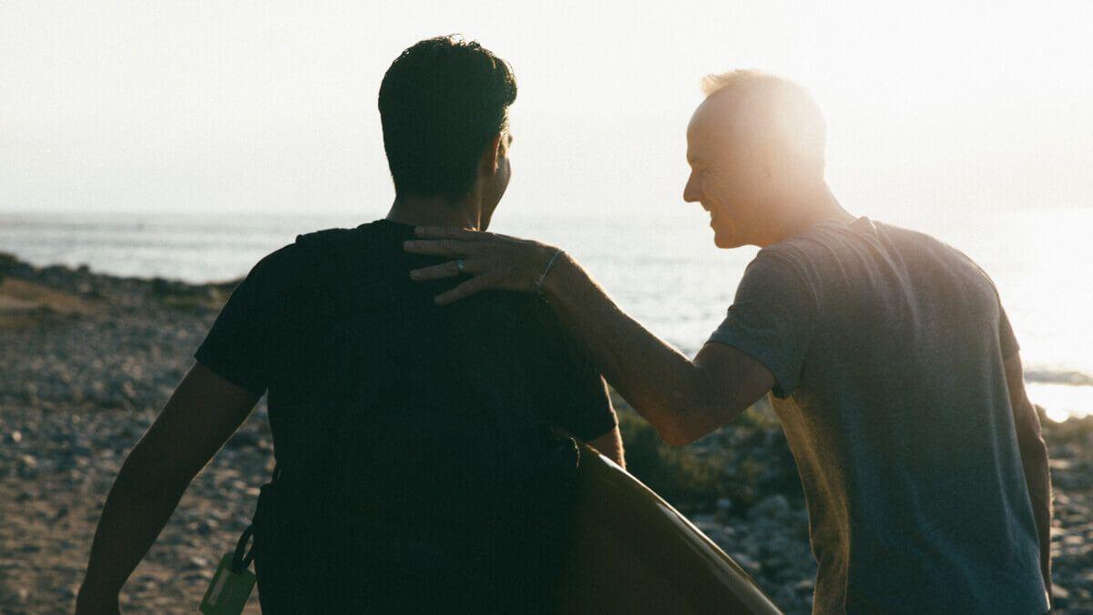 Two men walking on the beach with surfboard