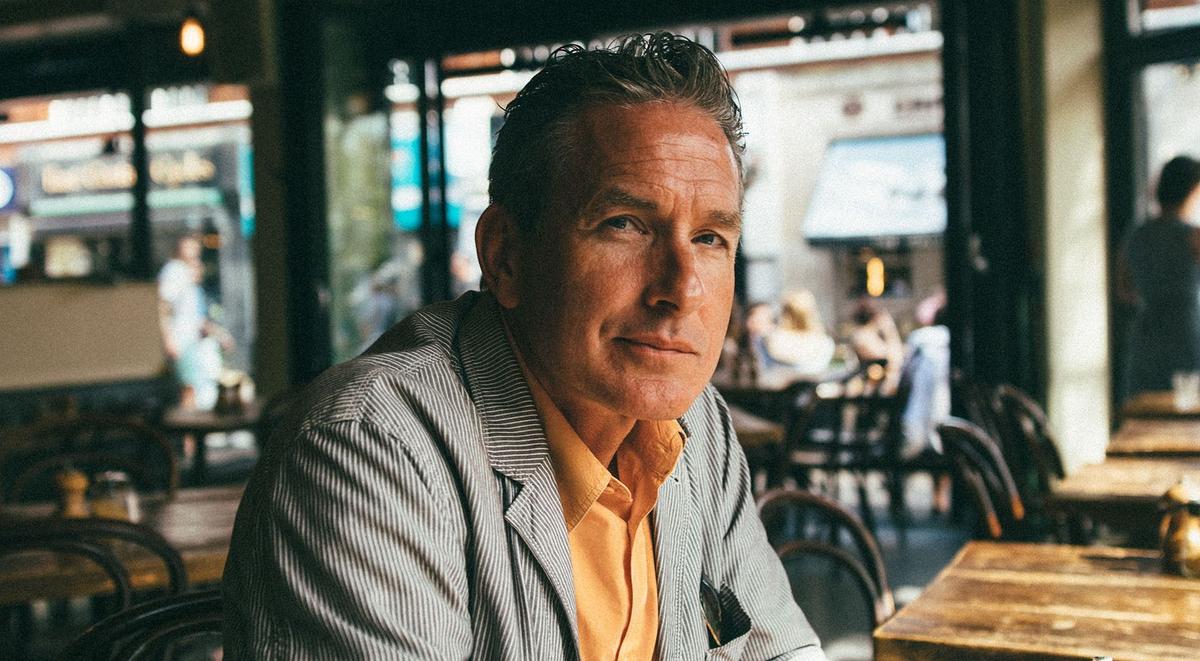 Middle-aged man sitting in cafe, looking to camera.