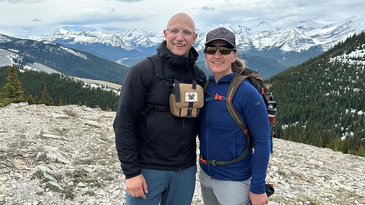 A mother and son pose on a mountain hike