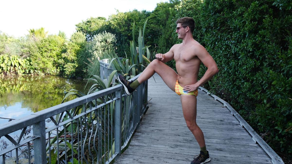 Man wearing speeds, stretching in a park.