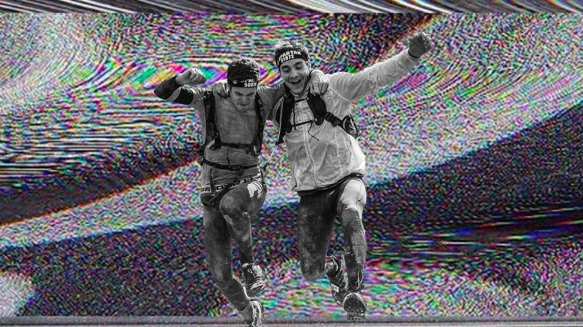 Two men arm in arm while running a trail together.