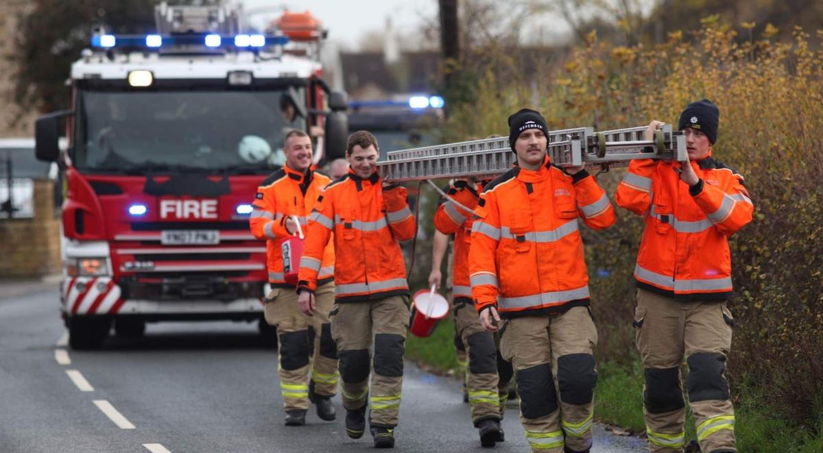 Fire engine following a fire crew carrying a 10 meter ladder on a road