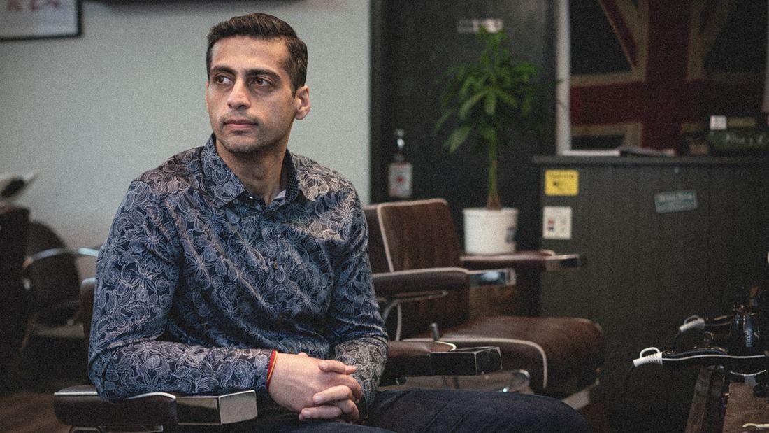 Anupam sat in a barber chair looking away from camera