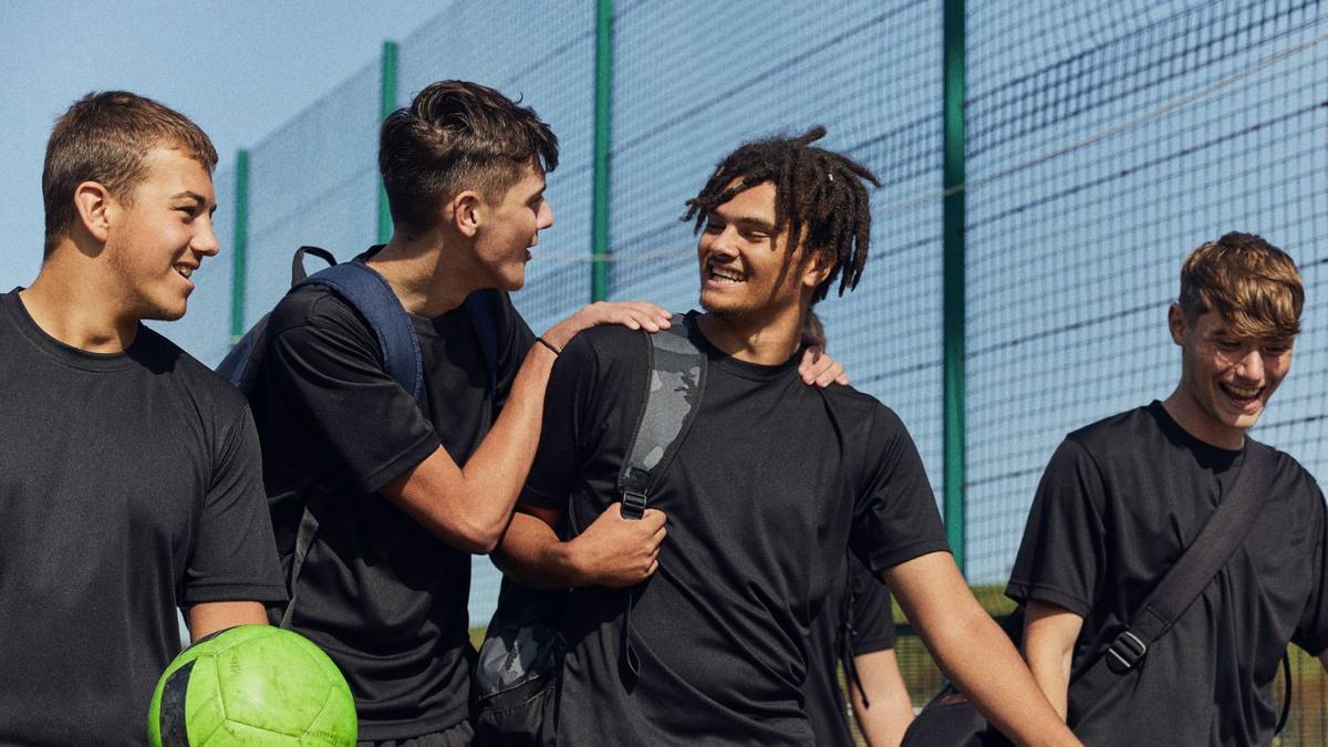 A photo of four young men walking and smiling with a football in hand.