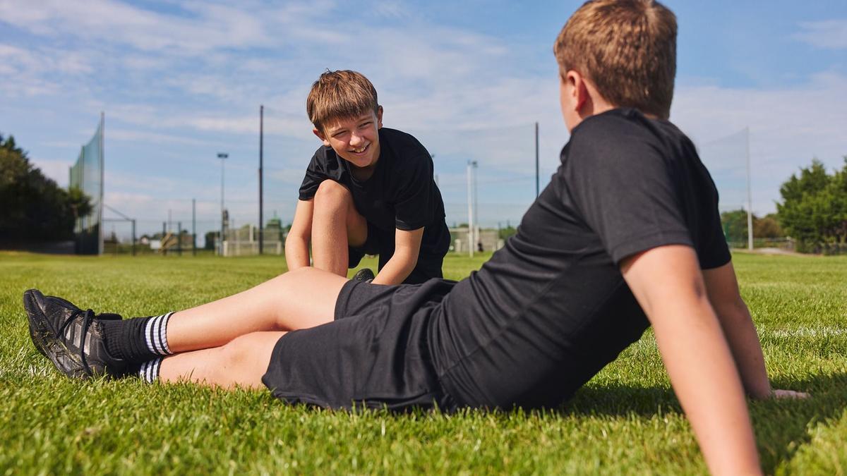 two young boys sat on a field talking