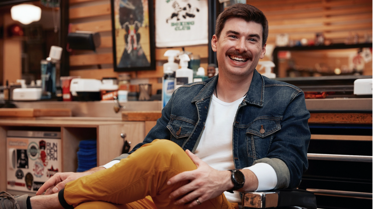 Man sitting in barber chair smiling at camera