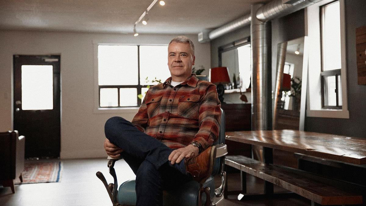 Mo Bro Glen Williams wears a spiffy plaid shirt sitting in a barbershop chair